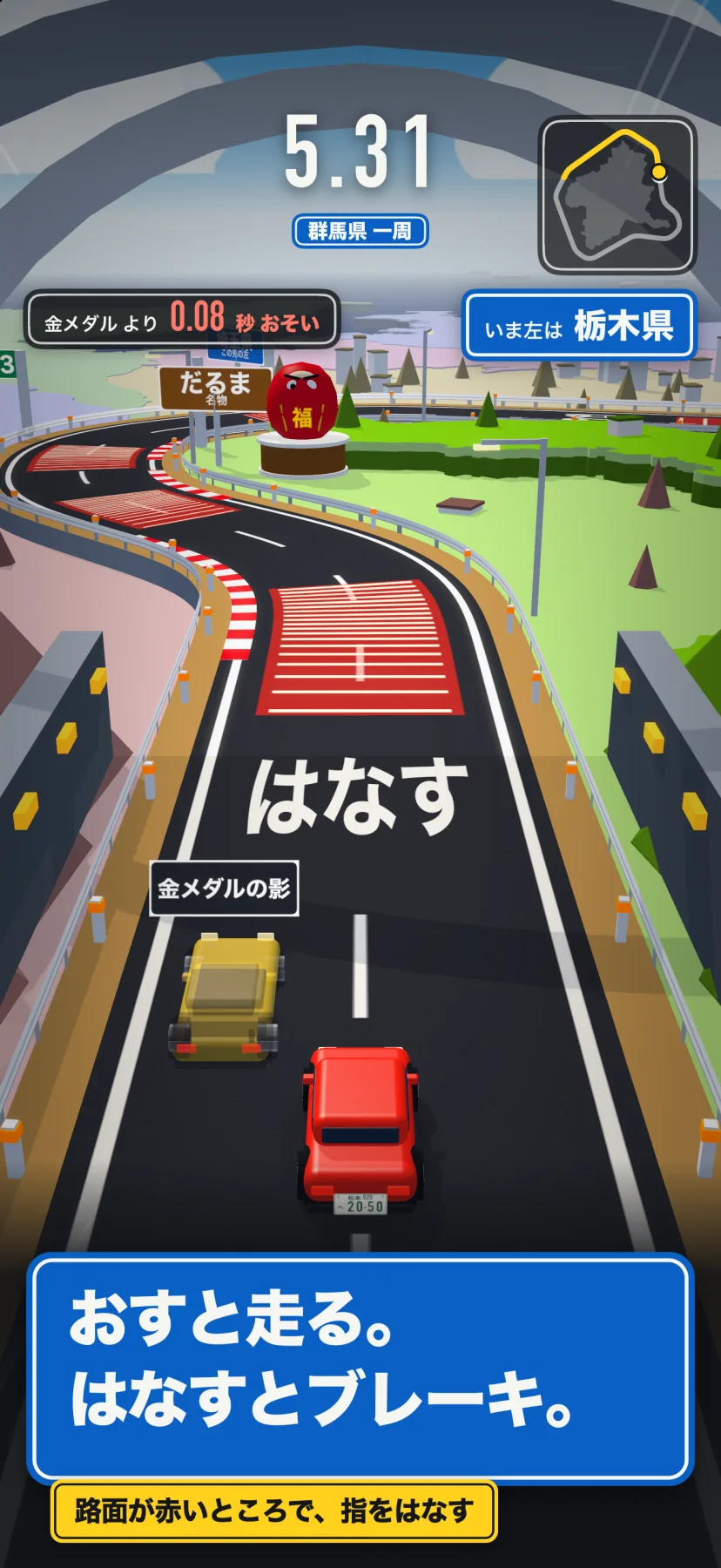 「おすと走る。はなすとブレーキ。」路面が赤いところで、指をはなす。群馬県一周の5.31秒の走行画面。カーブの手前の路面が赤く塗られ、大きく「はなす」の字。赤い車の左前に半透明の「金メダルの影」の車。左上に「金メダルより0.08秒おそい」、右上に「いま左は栃木県」と小さなコース図、道ばたに名物のだるまの立体物